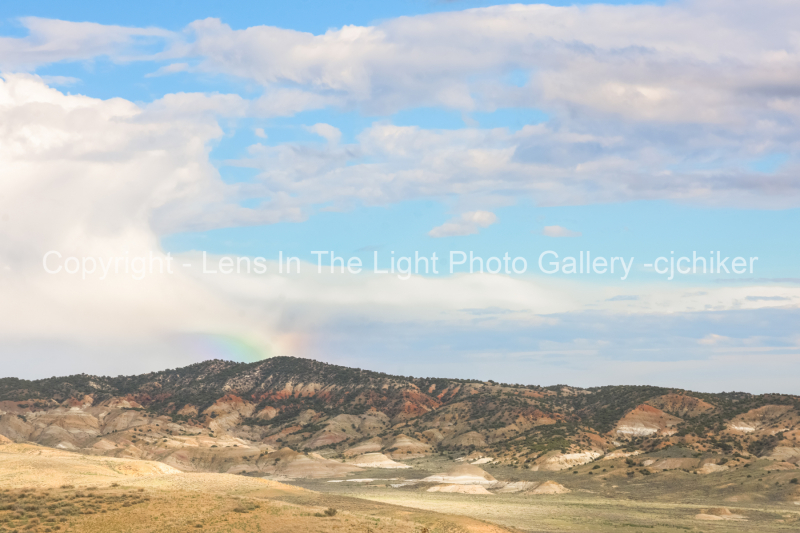 Striped-Hills-In-Sandwash-Basin-With-Rainbow-and-Clouds